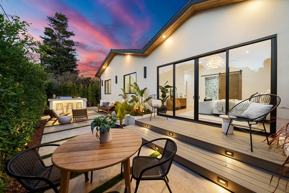 Modern patio with elegant furniture, lush plants, and ambient lighting at sunset